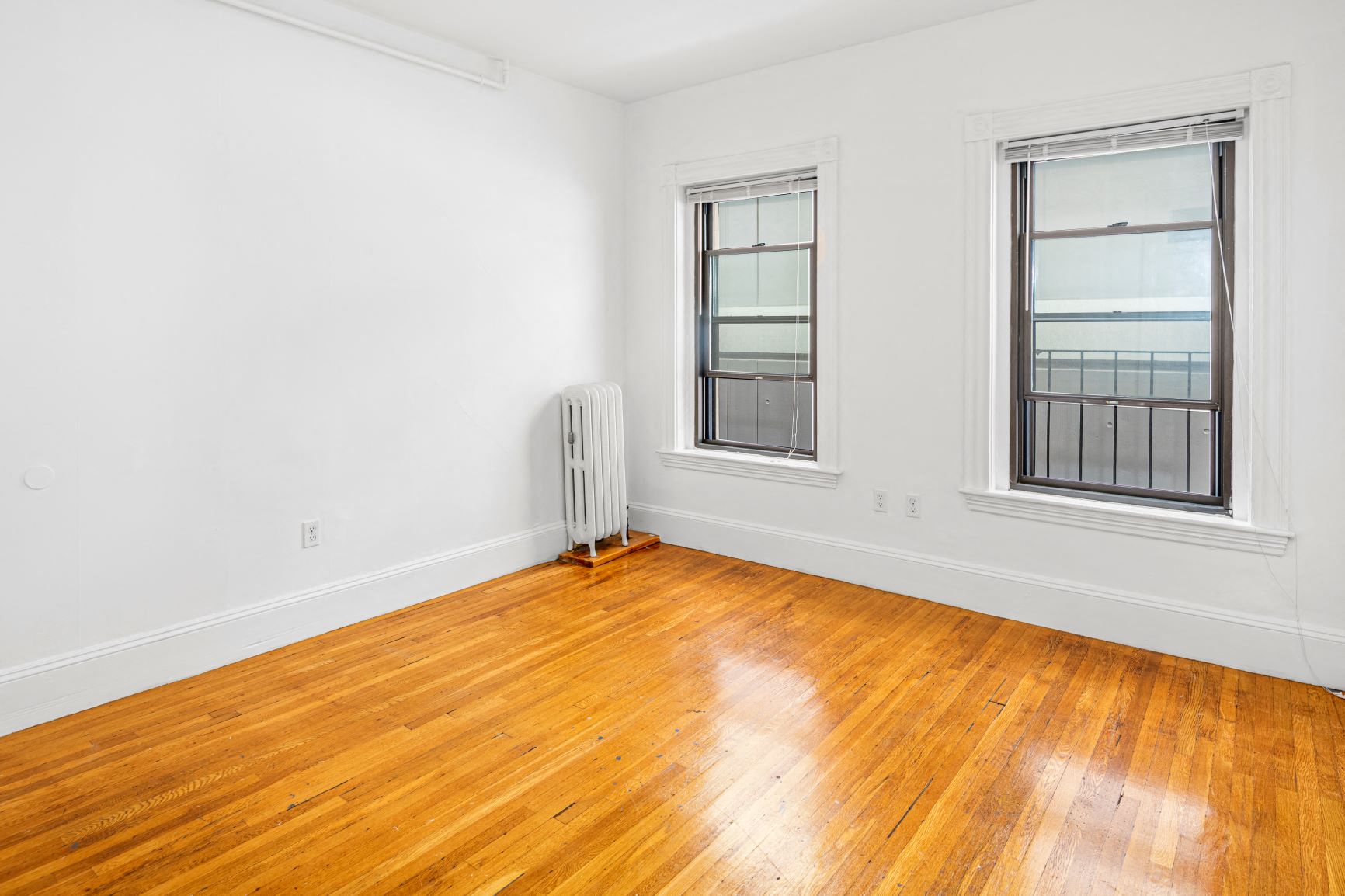 a living room with wood floors and three windows